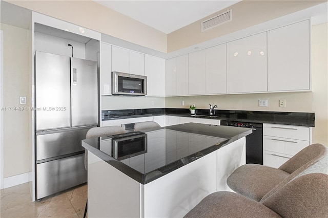 kitchen with sink, white cabinets, stainless steel appliances, and a kitchen island