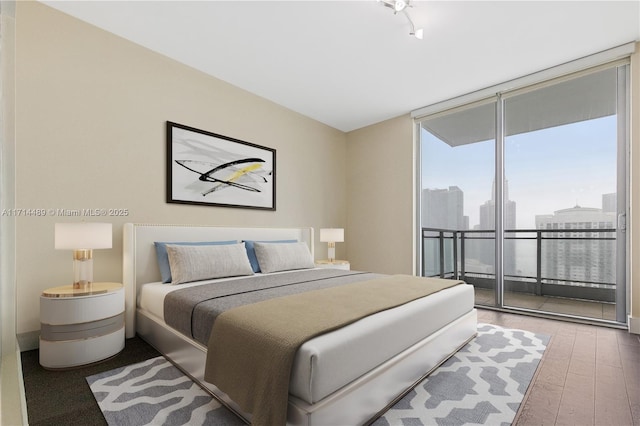 bedroom featuring access to outside, wood-type flooring, and a wall of windows