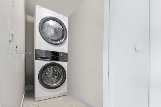 clothes washing area with light tile patterned flooring and stacked washer / dryer