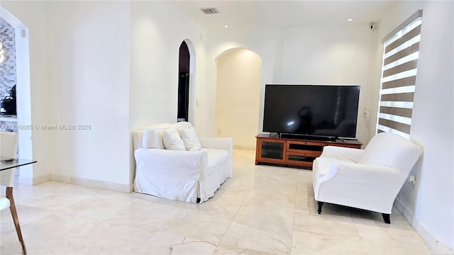 living room with arched walkways, visible vents, and baseboards