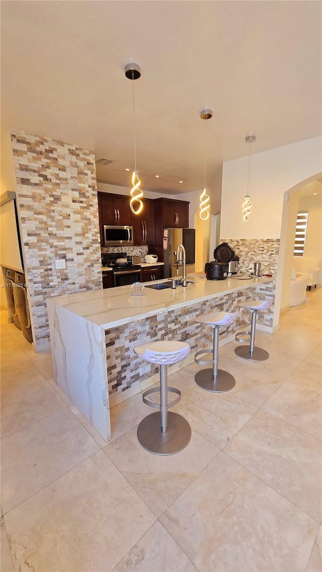 kitchen with stainless steel appliances, tasteful backsplash, a peninsula, and a kitchen breakfast bar