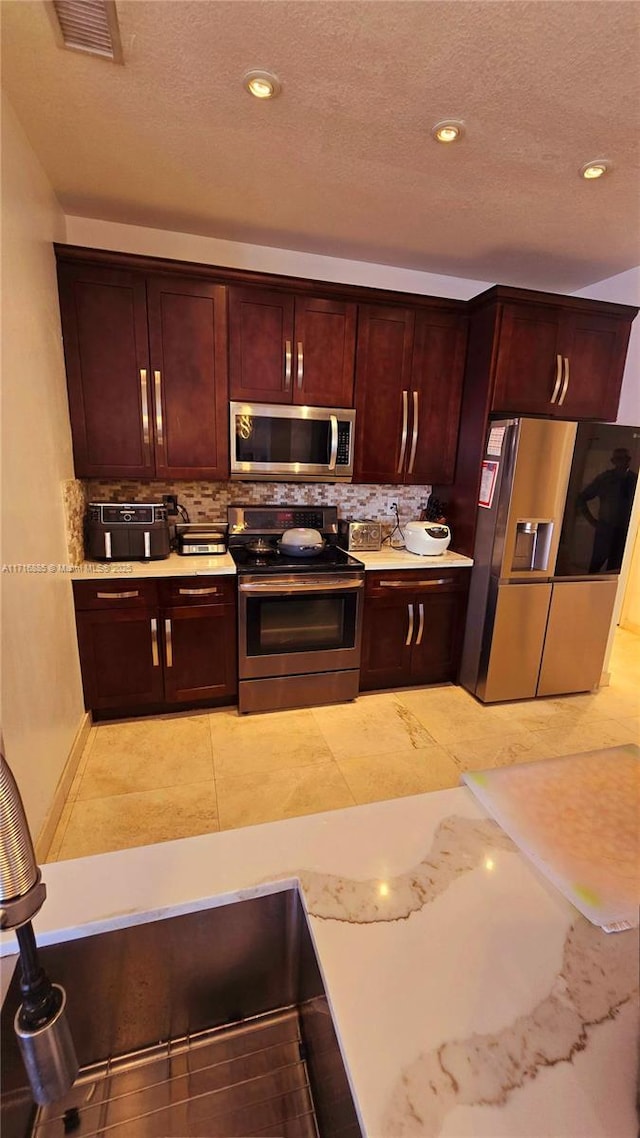 kitchen with stainless steel appliances, light countertops, and decorative backsplash