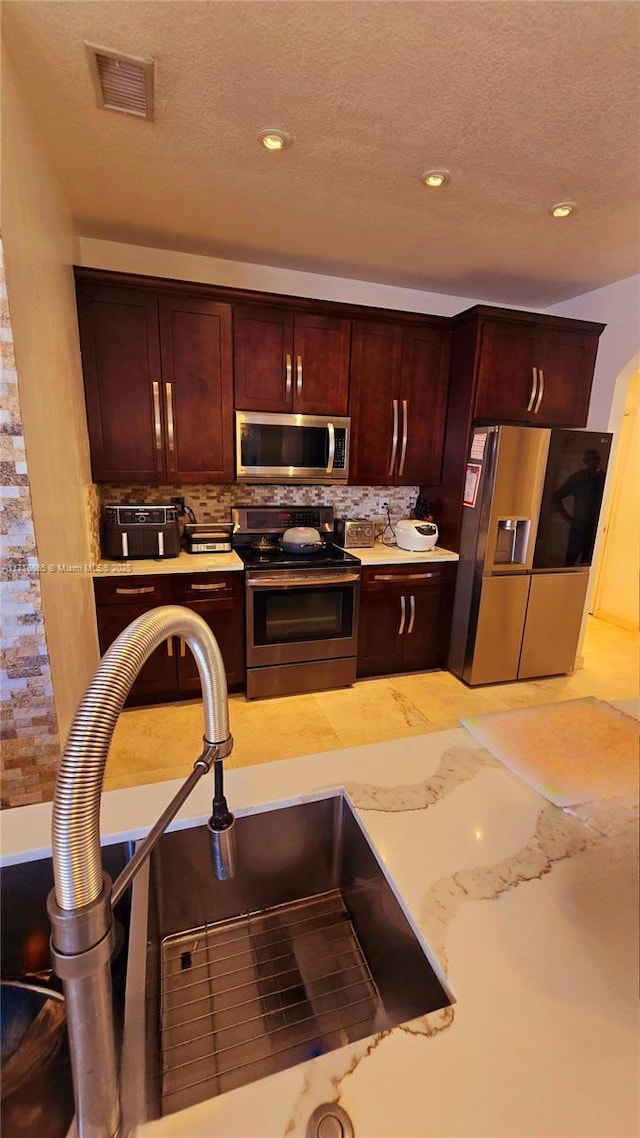 kitchen featuring a sink, stainless steel appliances, light countertops, and visible vents