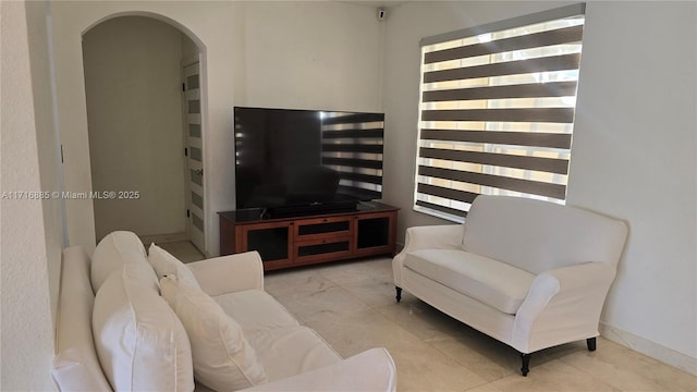 living area featuring arched walkways, built in features, and baseboards