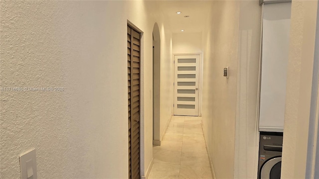 hallway featuring light tile patterned floors, recessed lighting, washer / clothes dryer, and a textured wall