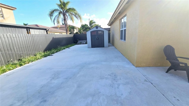 view of patio / terrace featuring a storage shed, a fenced backyard, and an outbuilding