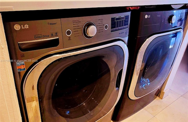 washroom with light tile patterned floors, laundry area, and washing machine and dryer