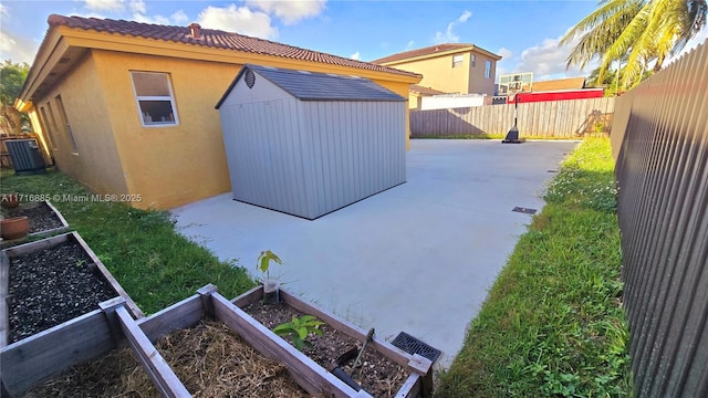 exterior space featuring a vegetable garden, a fenced backyard, a patio area, a shed, and stucco siding