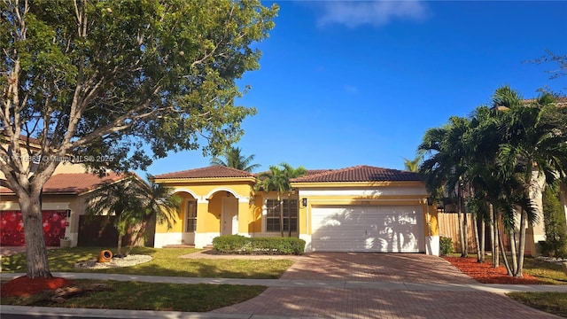 mediterranean / spanish house featuring a tiled roof, decorative driveway, an attached garage, and stucco siding