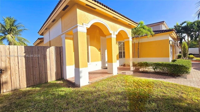 exterior space featuring a tiled roof, a lawn, and stucco siding