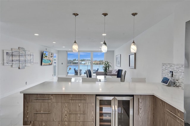 kitchen with backsplash, light stone countertops, hanging light fixtures, and wine cooler