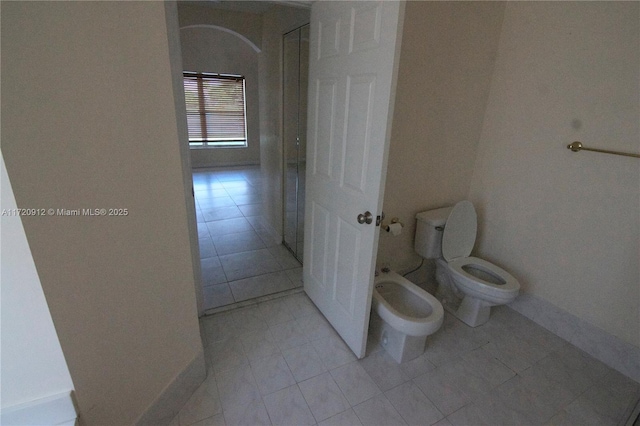 bathroom featuring toilet, tile patterned flooring, and a bidet