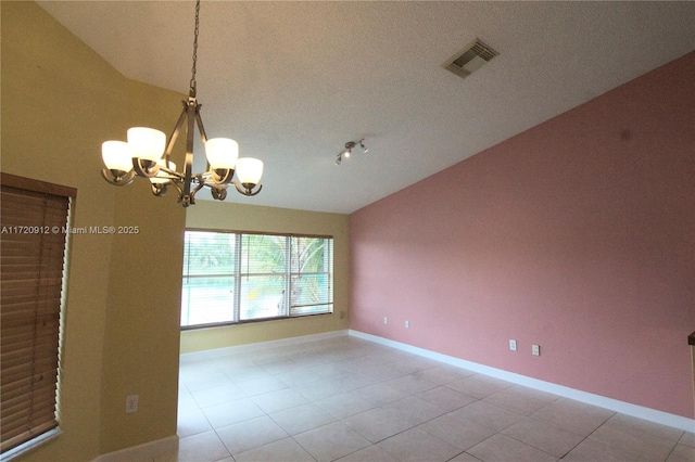 spare room featuring vaulted ceiling, light tile patterned floors, and a notable chandelier