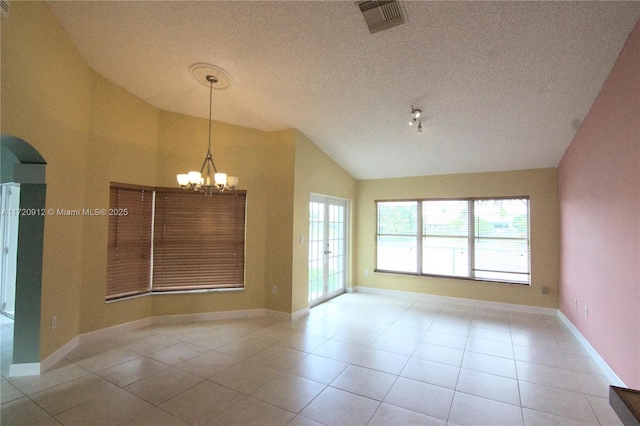 unfurnished room with a textured ceiling, an inviting chandelier, lofted ceiling, and light tile patterned floors