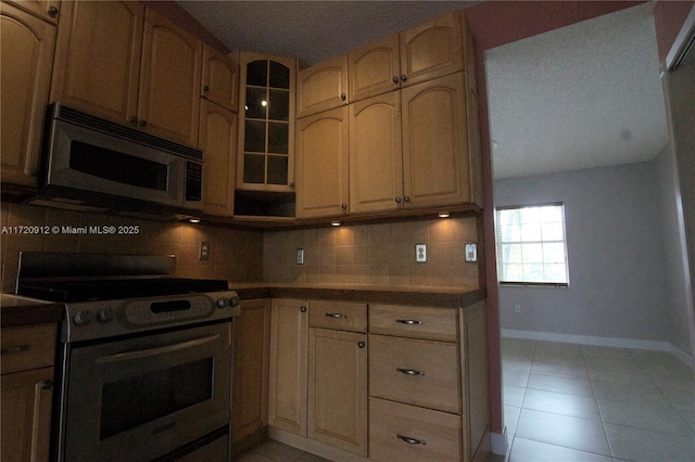 kitchen with appliances with stainless steel finishes, light tile patterned flooring, and tasteful backsplash