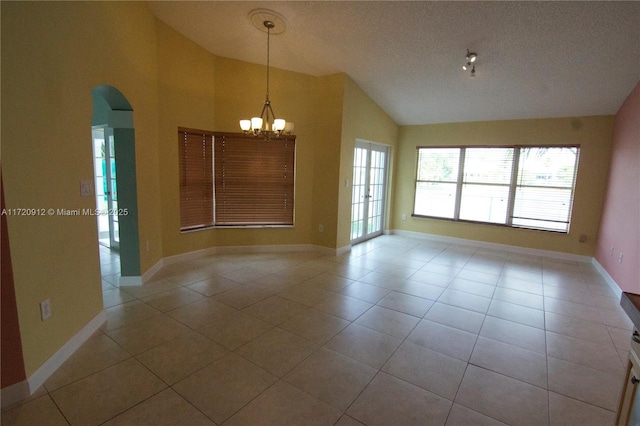 tiled spare room featuring a textured ceiling, vaulted ceiling, and a chandelier