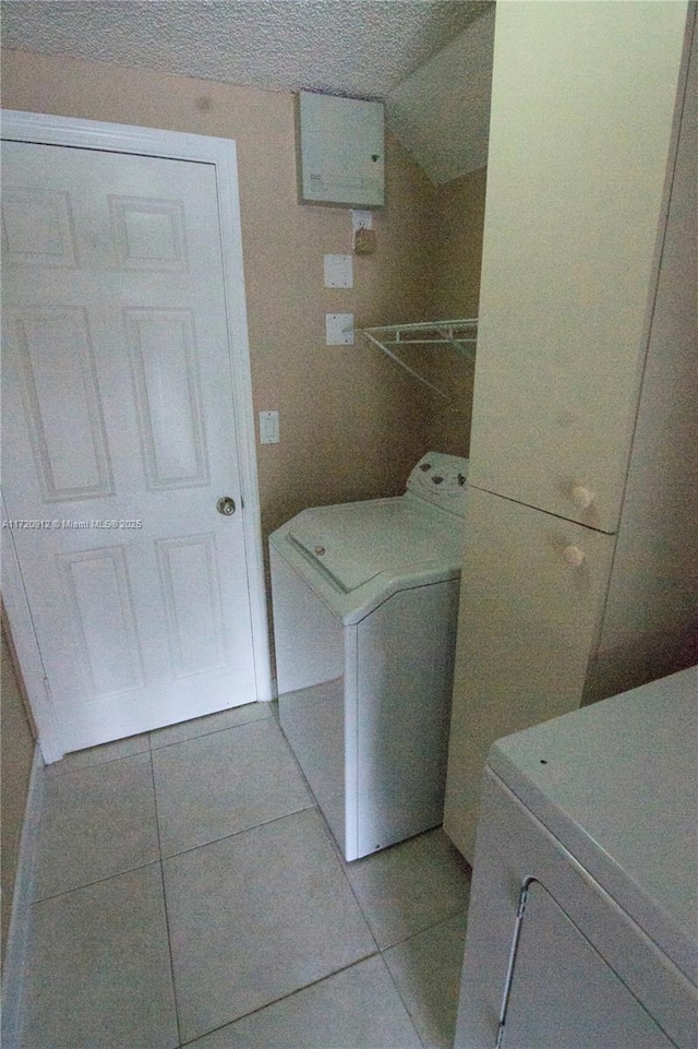 laundry area with washer and clothes dryer and light tile patterned floors