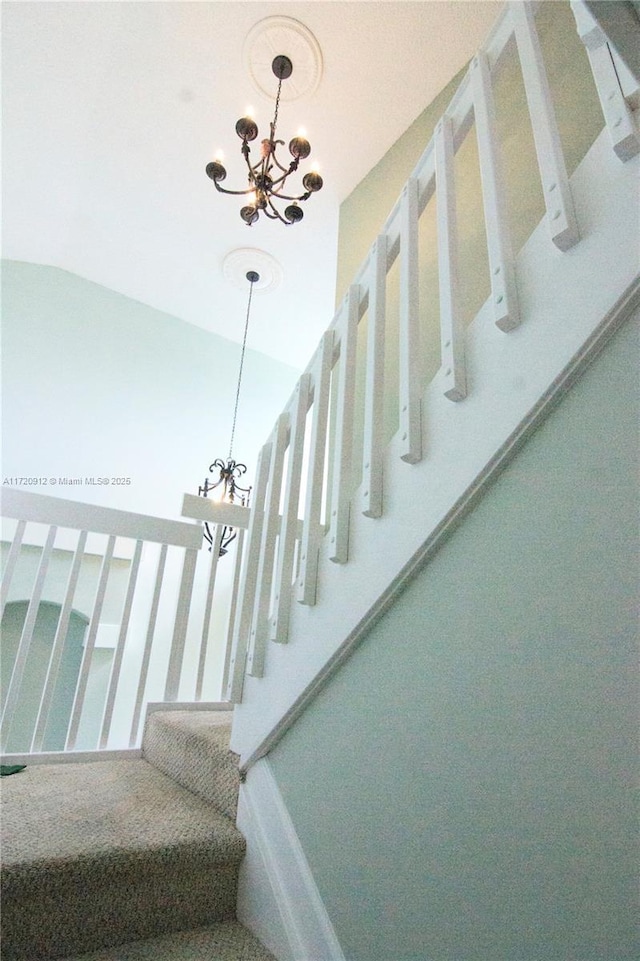 staircase with lofted ceiling and an inviting chandelier