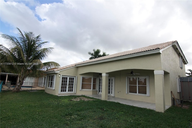 back of property featuring ceiling fan, french doors, a patio, and a lawn