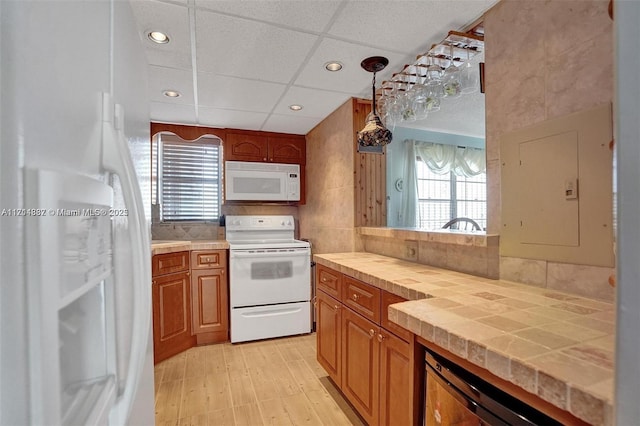 kitchen featuring decorative light fixtures, tile countertops, a drop ceiling, and white appliances