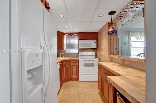 kitchen featuring decorative light fixtures, tasteful backsplash, sink, white appliances, and a paneled ceiling