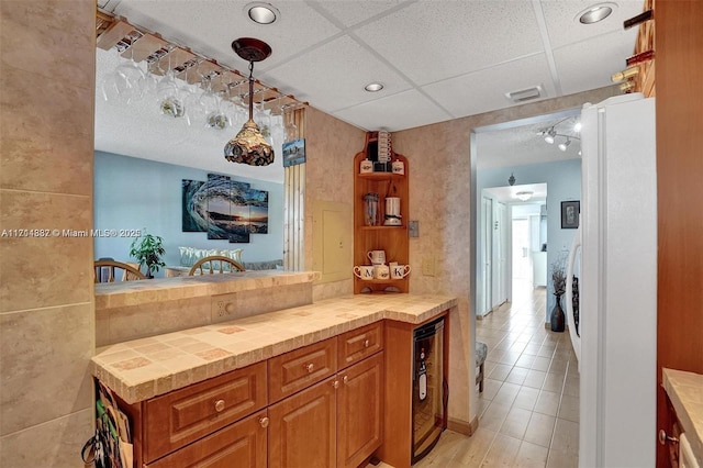 kitchen with pendant lighting, beverage cooler, a paneled ceiling, and white fridge