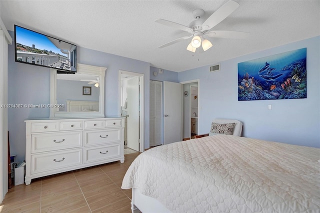 tiled bedroom with ceiling fan, ensuite bath, and a textured ceiling