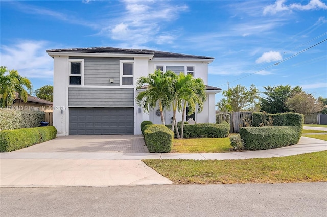 view of front of home with decorative driveway, an attached garage, and fence