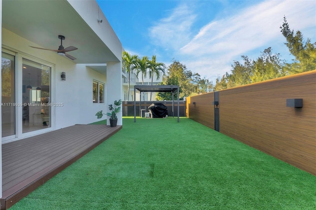 view of yard with ceiling fan, a pergola, and a wooden deck