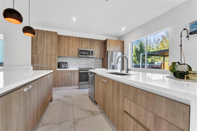 kitchen featuring decorative backsplash, stainless steel appliances, hanging light fixtures, and sink