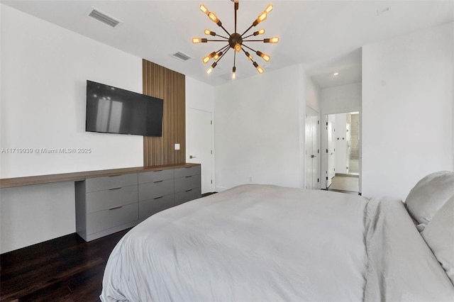 bedroom featuring a chandelier, dark hardwood / wood-style flooring, and ensuite bath