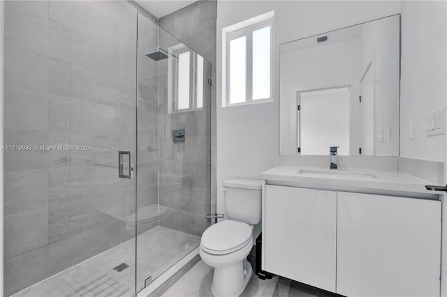 bathroom featuring vanity, a shower with shower door, and toilet