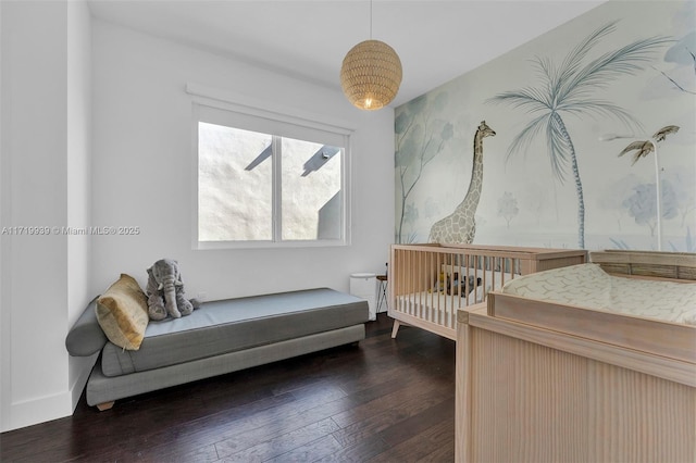 bedroom with dark wood-type flooring and a nursery area