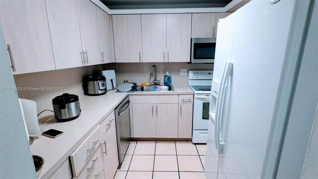 kitchen featuring light tile patterned flooring, sink, stainless steel appliances, and light brown cabinetry