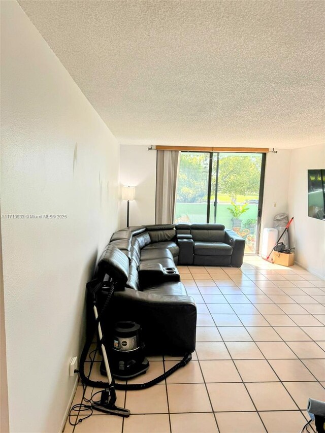 living room featuring a textured ceiling, floor to ceiling windows, and light tile patterned flooring