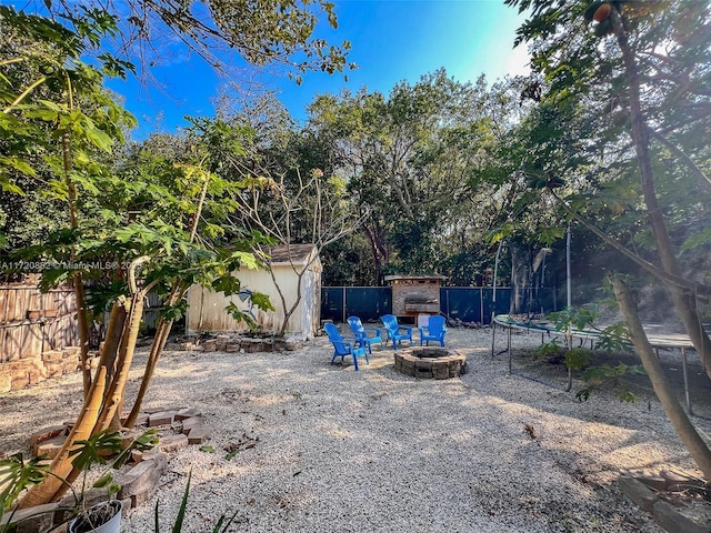 view of yard featuring a trampoline and an outdoor fire pit