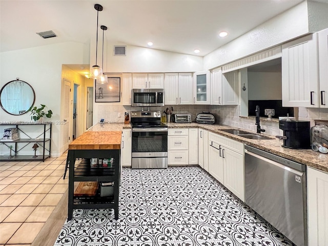 kitchen with white cabinetry, sink, stainless steel appliances, and vaulted ceiling