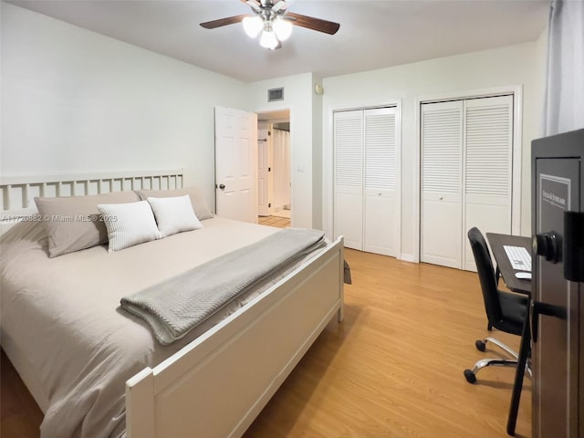 bedroom featuring light wood-type flooring, two closets, and ceiling fan