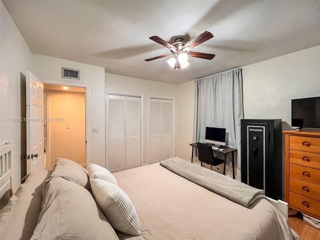 bedroom with ceiling fan, light wood-type flooring, and two closets