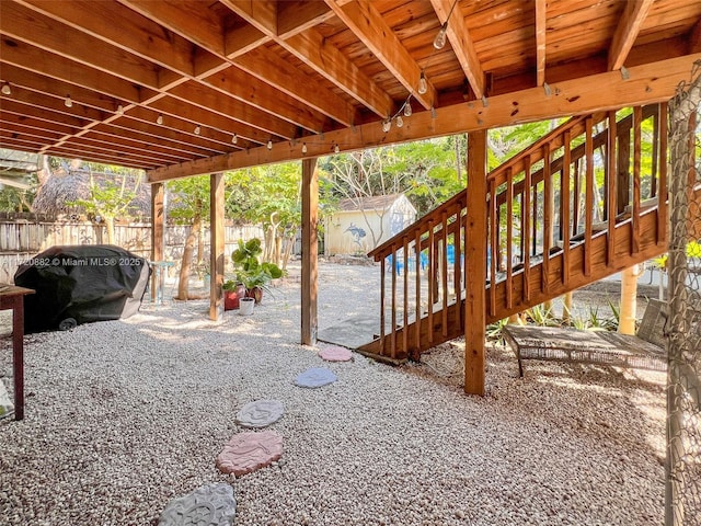 view of patio with a wooden deck, a storage shed, and a grill