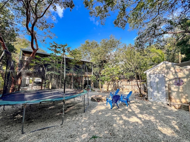 view of yard with a trampoline, a fire pit, and a storage shed