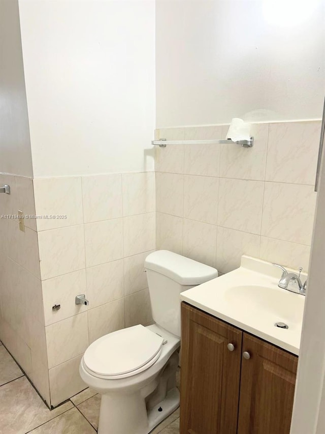 bathroom with vanity, toilet, tile patterned flooring, and tile walls