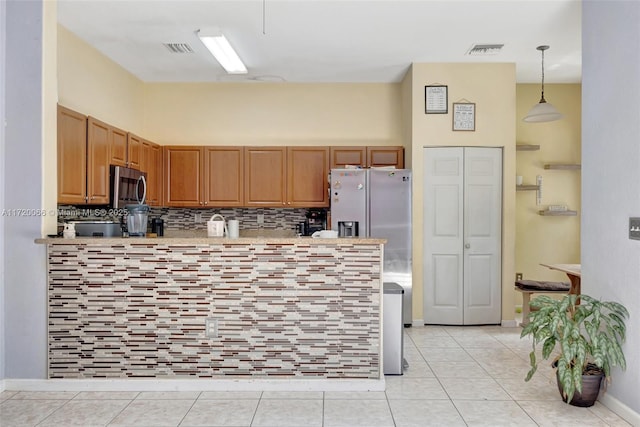 kitchen with light tile patterned floors, tasteful backsplash, decorative light fixtures, kitchen peninsula, and stainless steel appliances