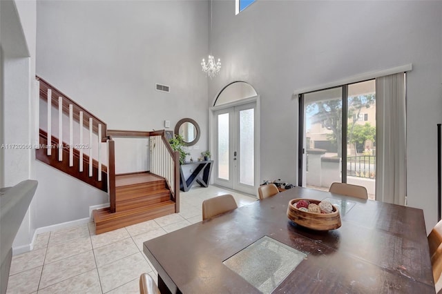 dining area featuring french doors, light tile patterned floors, a chandelier, and a high ceiling