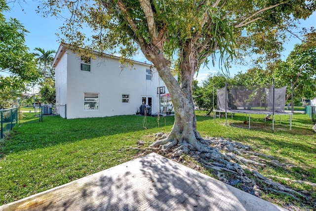 rear view of house featuring a patio, a trampoline, cooling unit, and a lawn