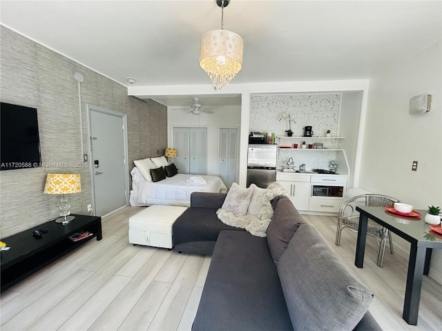 bedroom featuring an inviting chandelier, stainless steel fridge, beam ceiling, light hardwood / wood-style floors, and multiple closets