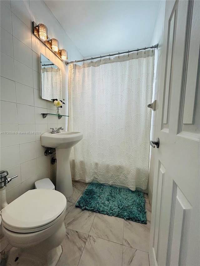 bathroom featuring curtained shower, toilet, and tile walls