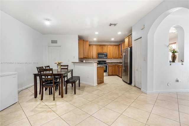 kitchen featuring kitchen peninsula, stainless steel appliances, and light tile patterned floors