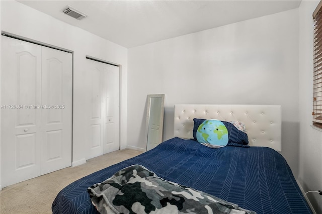 bedroom featuring light carpet and multiple closets