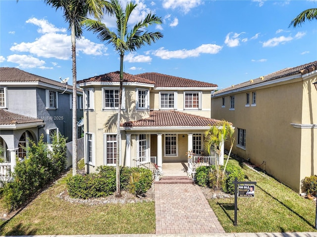 mediterranean / spanish home with covered porch and a front lawn